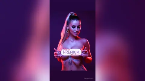 Glamorous woman with blonde ponytail posing in moody pink lighting for premium content.