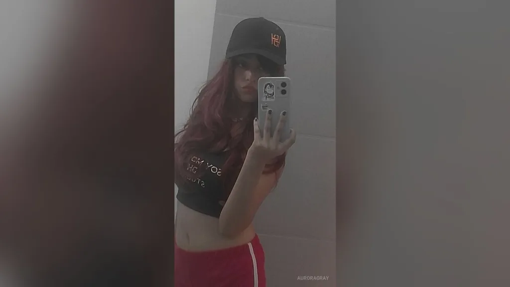 AuroraGray β AuroraGray takes a mirror selfie wearing a black crop top, red shorts, and a black baseball cap.
