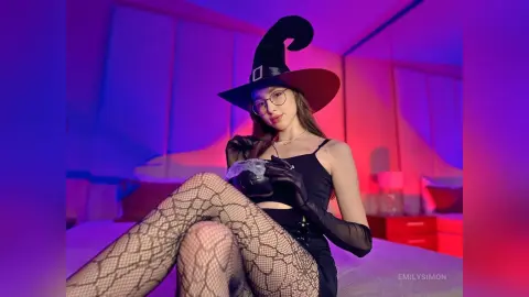 Young woman in a witch costume and fishnet tights posing in moody purple lighting.