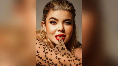 FiorellaRossi licks her red-painted lips while wearing a leopard print mesh top.