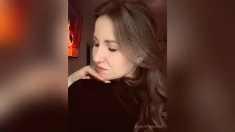 MargaritaHafele poses with her hand under her chin, showing her long brown hair and wearing a black top.