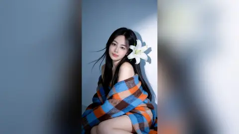 Young woman wrapped in a blue and orange plaid blanket posing against a light blue background with a white lily.