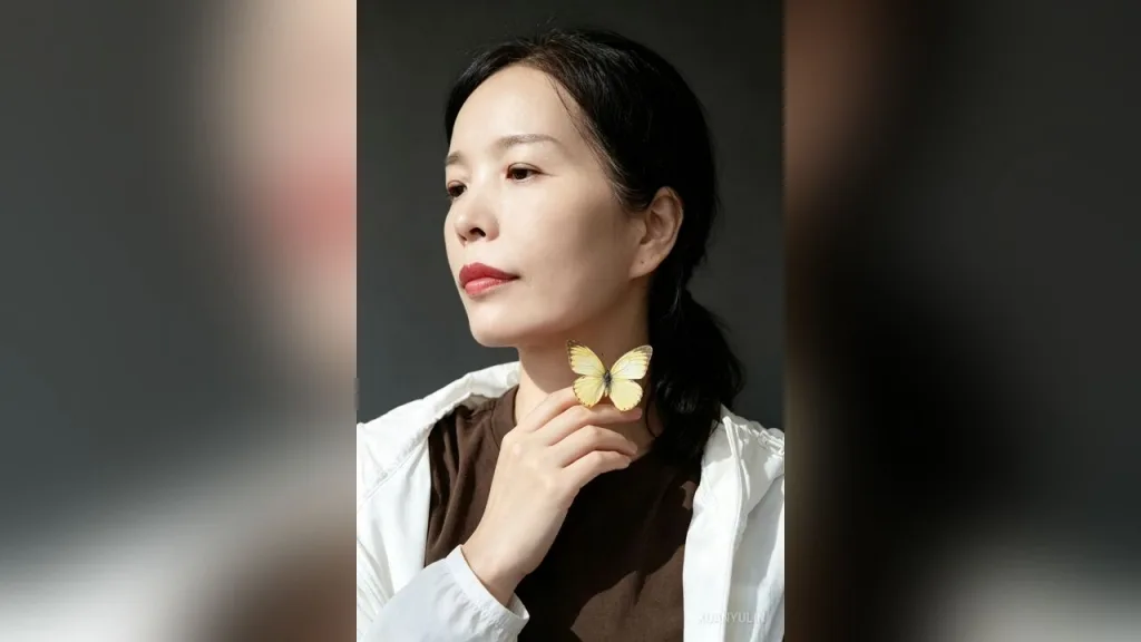 XuanyuLin poses in a red cheongsam with red flowers in her hair against a dark background.