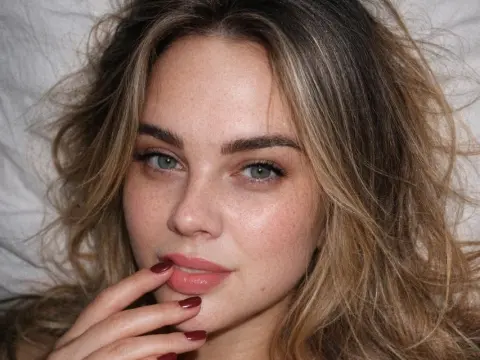 Close-up portrait of a freckled woman with messy blonde hair looking into the camera in a soft, natural mood.