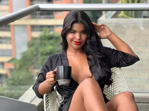 Smiling woman in a black satin robe sitting on a balcony with a coffee mug during a relaxing morning.