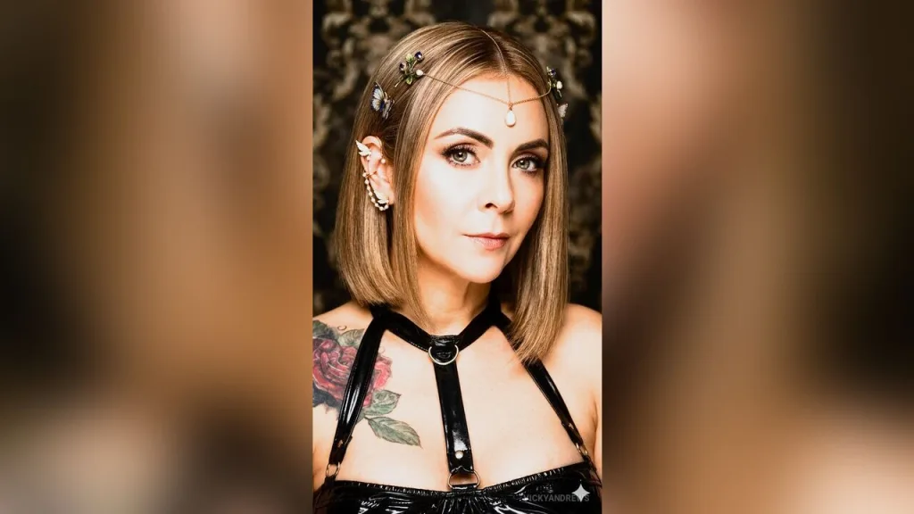 VickyAndrews — VickyAndrews wears a black leather harness and a gold headpiece while posing with her blonde bob hair.