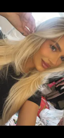 Angellxoxo — Angellxoxo poses with her long blonde hair, wearing a black t-shirt and looking directly at the camera.