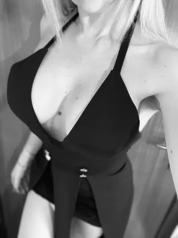 Dolcegiorgia36 poses in a low-cut black halter top that shows off her cleavage and blonde hair in this black and white photo.