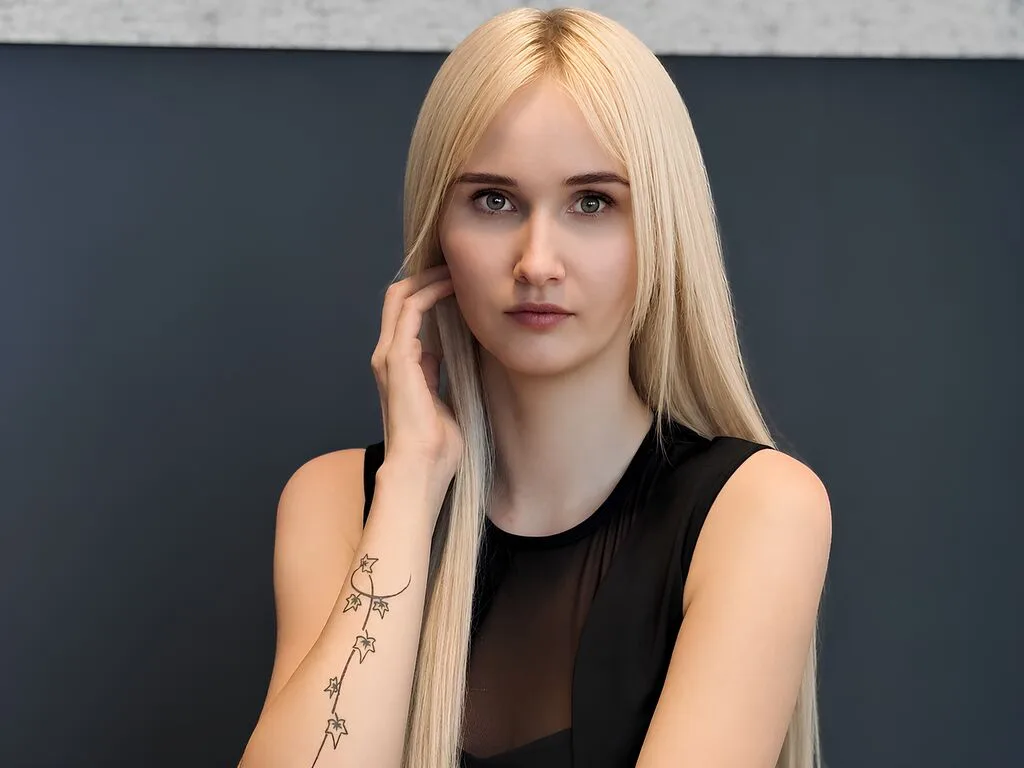 LiliMew — LiliMew with long blonde hair poses in a black sleeveless top against a dark background.