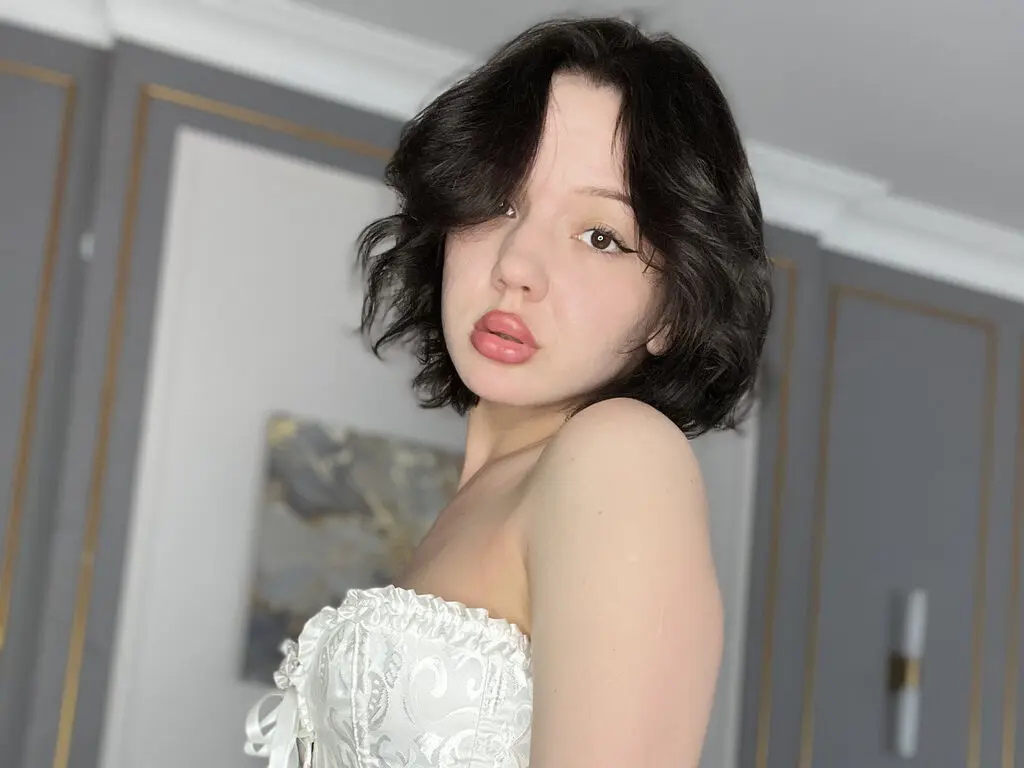 Young woman in a white lace corset top posing in a bright, modern room with a soft, dreamy mood.