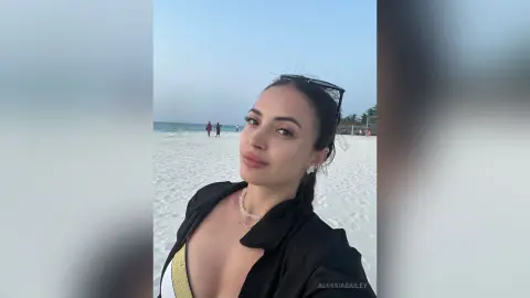 Beautiful woman in a black beach cover-up smiling on a sunny white sand tropical beach.