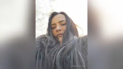Close-up portrait of a woman with long flowing hair in a soft, natural outdoor setting with a dreamy mood.