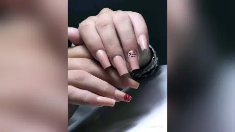 Close-up of long nude almond nails featuring a cute red kiss nail art design.