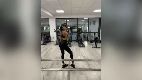 Athletic woman in black gym wear standing in a modern bright fitness center gym.