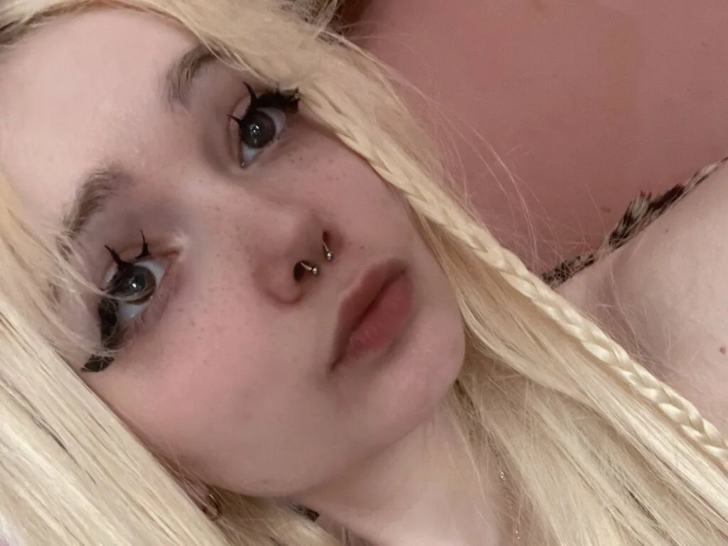 LaticiaDemetris with long blonde hair and red lipstick looks into the camera with a nose ring.