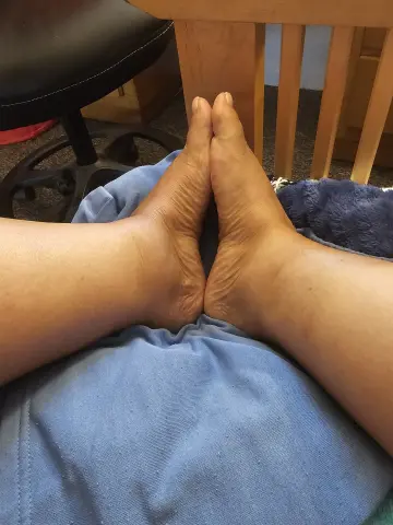 Close-up of bare feet resting on blue denim jeans in a cozy indoor setting.