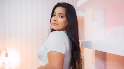 Young woman with long dark hair wearing a white t-shirt in a bright, minimalist indoor setting.