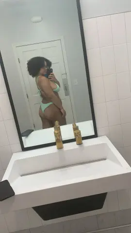 PrincessBiancaHoney poses in a light green bikini, showing her bare buttocks and curves in a bathroom mirror selfie.