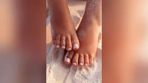 Close-up of sandy feet with white pedicure resting on a sunny beach for a relaxing summer vacation mood.