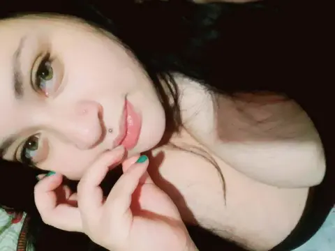 Close-up portrait of a young woman with dark hair and green eyes posing with a thoughtful expression.