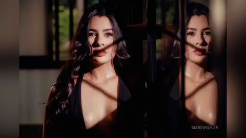 Glamorous woman in a black plunging neckline dress posing in dramatic sunlight and shadows.