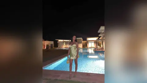NicoleBella stands poolside at night wearing a short, tight lime green dress and matching heels.