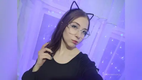 Young woman with glasses and cat ear headband posing in soft purple lighting.