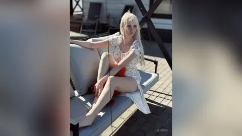 LiliMew — LiliMew sits on an outdoor lounge chair wearing a short white floral sundress.
