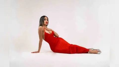 Elegant woman in a sleek red evening gown posing against a white studio background.