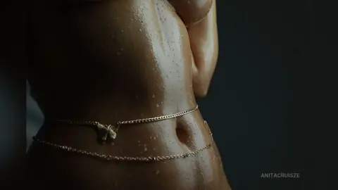 Anita shows off her wet, glistening skin and a gold waist chain around her bare stomach.