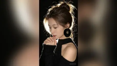 Elegant woman in a black knit sweater and large black fuzzy earrings posing in dramatic studio lighting.