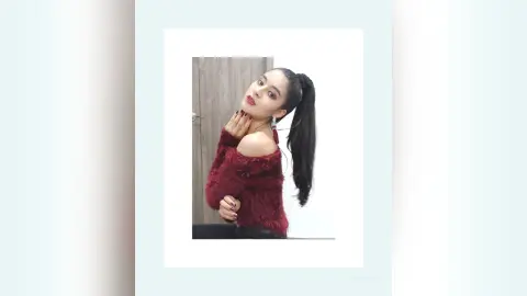Young woman in a cozy burgundy off-the-shoulder sweater posing with a confident expression indoors.