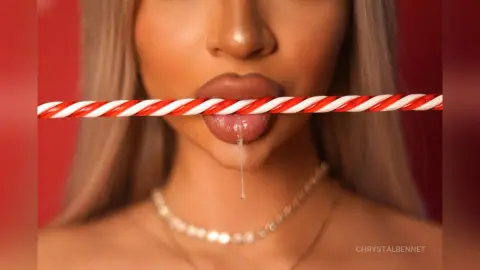 Close-up of a woman with blonde hair biting a red and white striped candy cane against a red background.