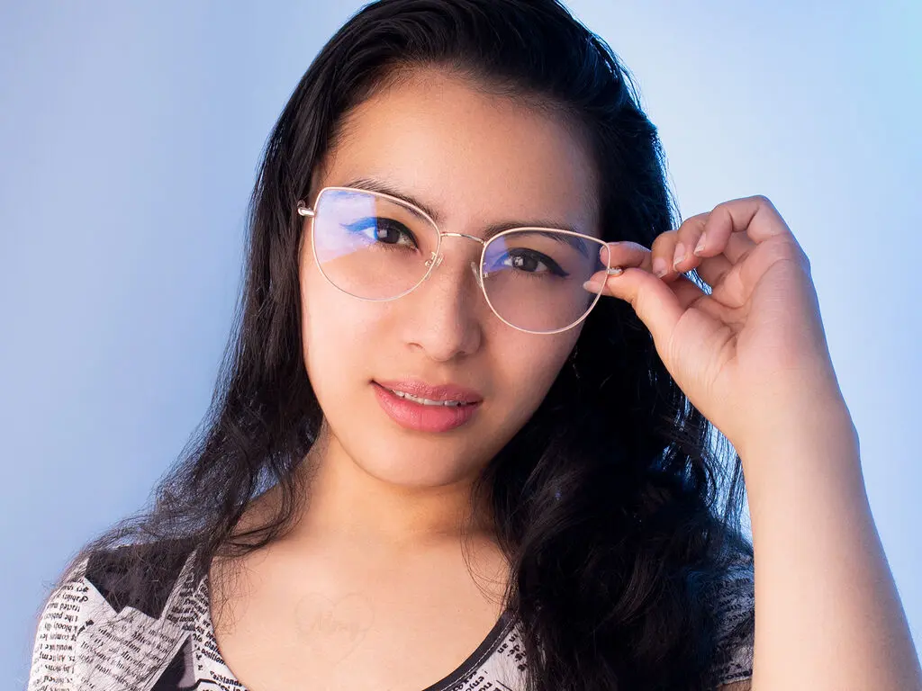 Smiling young woman with long dark hair wearing stylish silver wire-frame glasses against a blue background.