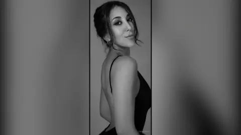 Elegant woman in a black backless dress posing for a moody black and white portrait.