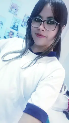 Young woman with long dark hair and glasses wearing a white and navy t-shirt in a bright room.