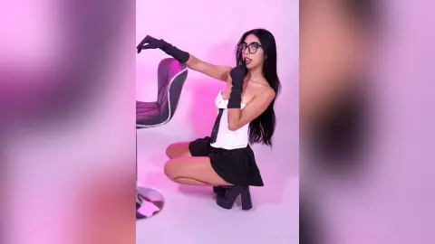 Stylish woman in white crop top, black skirt, and gloves posing against a pink studio background.