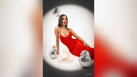 Glamorous woman in a red evening gown posing with disco balls for a festive New Year's Eve celebration.