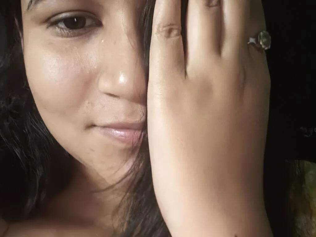 RinnyDubey looks into the camera with long dark hair partially covering her face.
