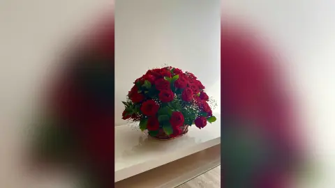 SaraBeleno is not visible in this photo, which features a large bouquet of red roses in a basket sitting on a white shelf.