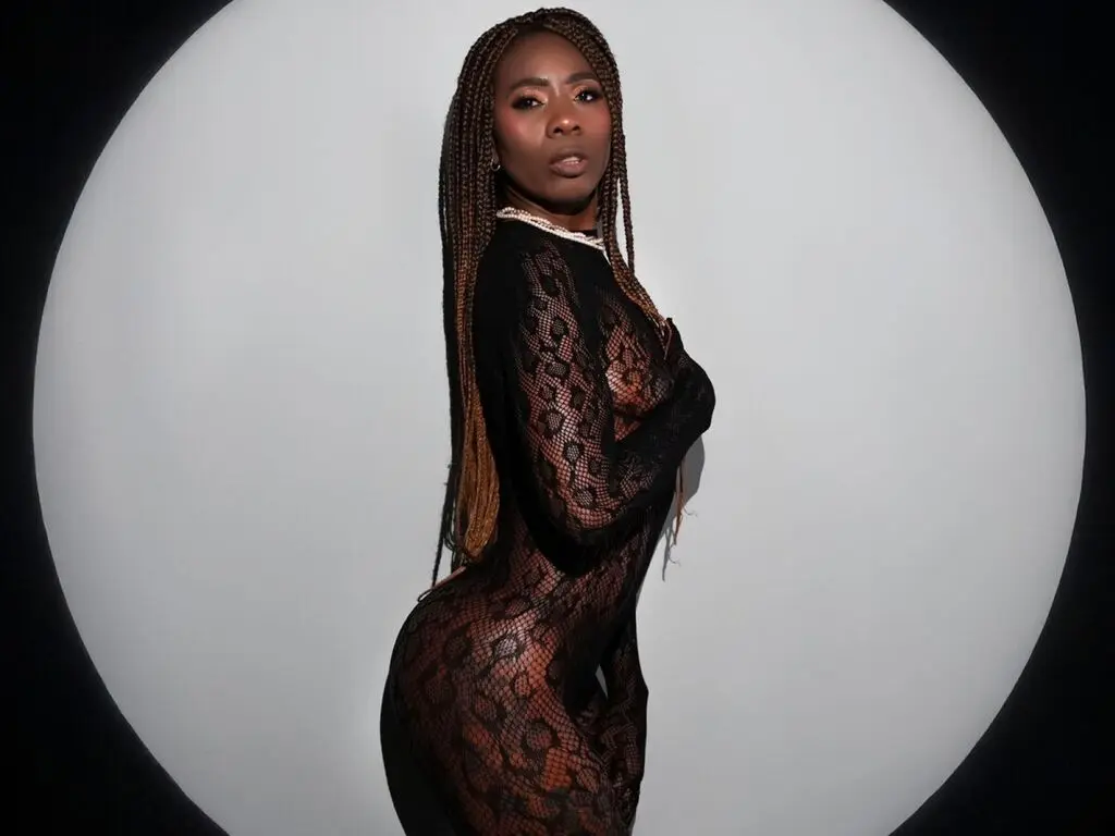 Elegant Black woman in a black lace bodysuit posing against a dramatic circular spotlight background.