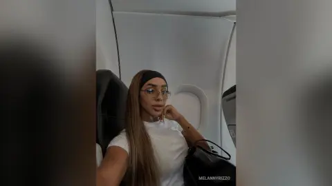Stylish woman in a white t-shirt sitting in an airplane cabin with a relaxed travel mood.
