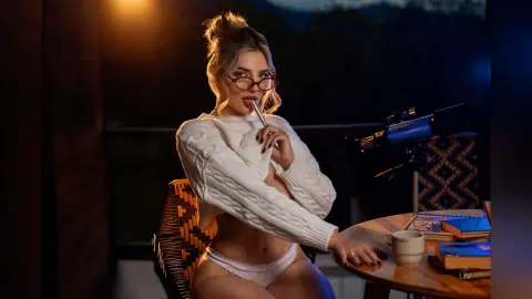 Blonde woman in a white cable knit sweater and lace briefs relaxing on a balcony at night.