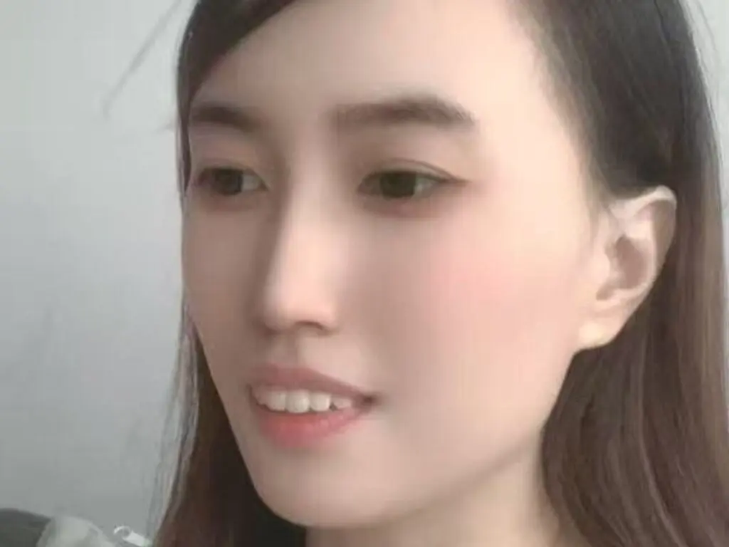 Close-up portrait of a young woman with long dark hair and natural makeup looking calmly at the camera.