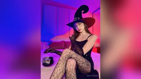 Young woman in witch costume and fishnet tights holding a cauldron in moody purple lighting.