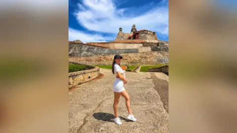 LauraRiveiro — LauraRiveiro stands on a stone path wearing a white tank top and white shorts under a blue sky.
