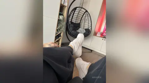 AriaVex relaxes in black lounge pants and white sneakers while sitting in a room with a black hanging egg chair.