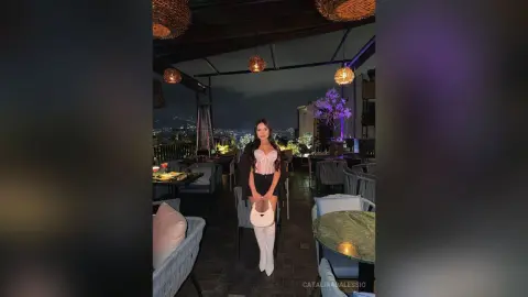 Stylish woman in a white corset top and black shorts enjoying a night out at a rooftop lounge bar.