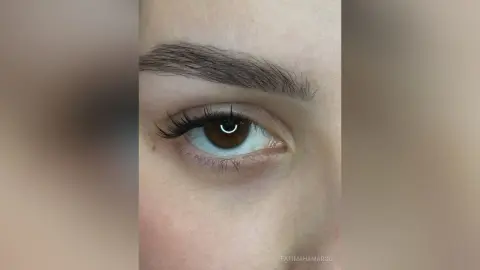Close-up of a brown eye with long black eyelashes and groomed eyebrows for natural beauty makeup inspiration.