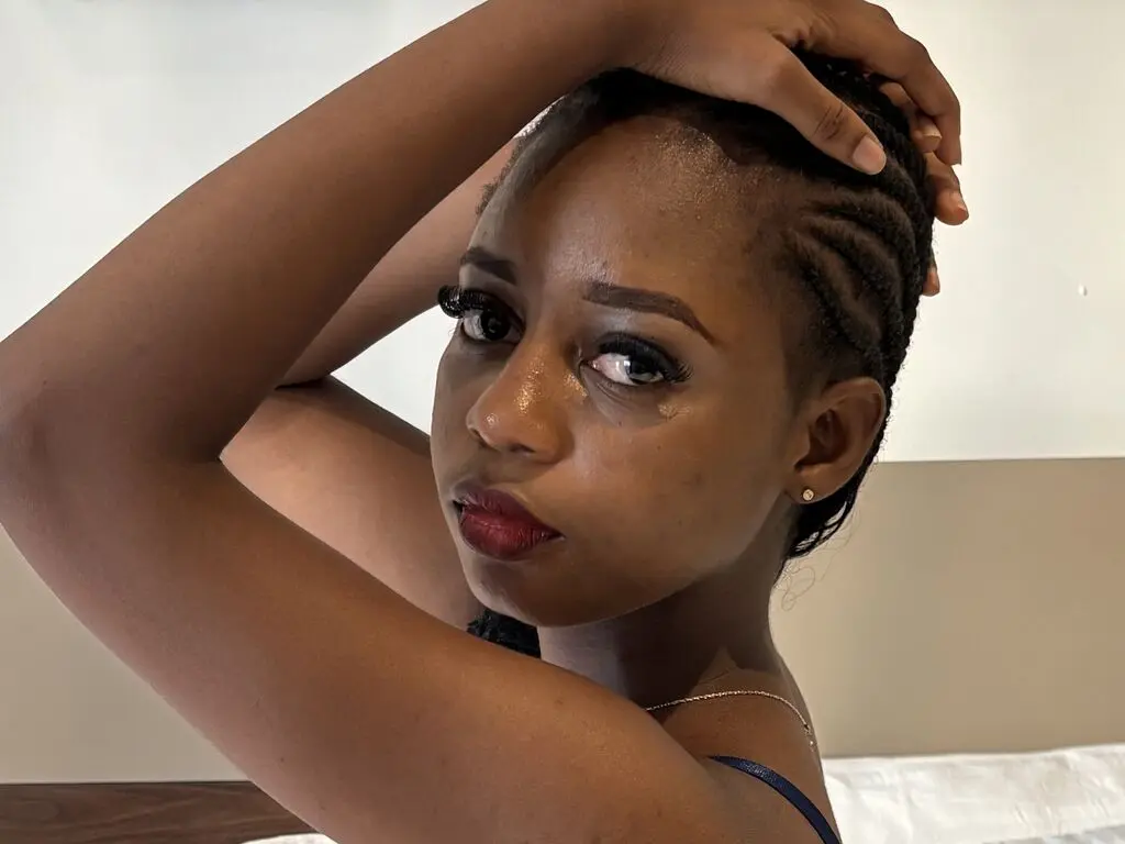 Close-up portrait of a young Black woman with braided hair posing with a thoughtful expression indoors.